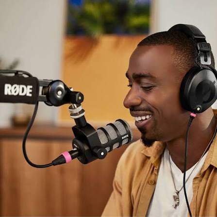 Promotional image of a presenter using a RØDE PodMic with headphones