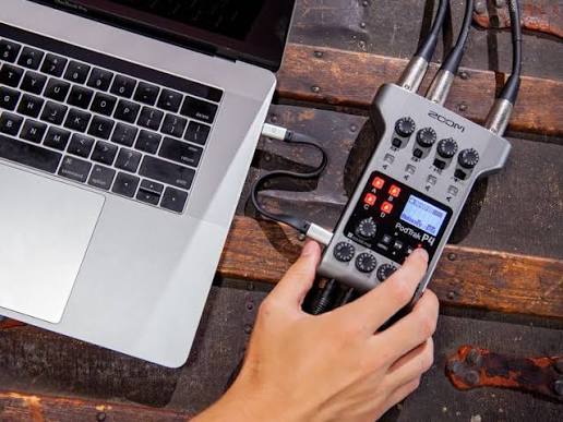 Promotional image of a Zoom PodTrak P4 recorder being operated beside a laptop