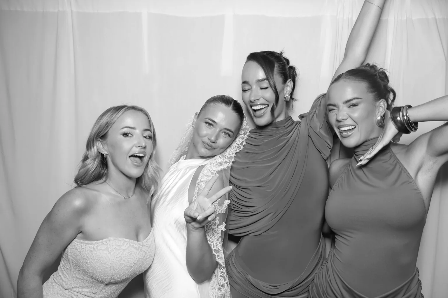 Four wedding guests laughing together in a black-and-white Selfie Glam Booth portrait