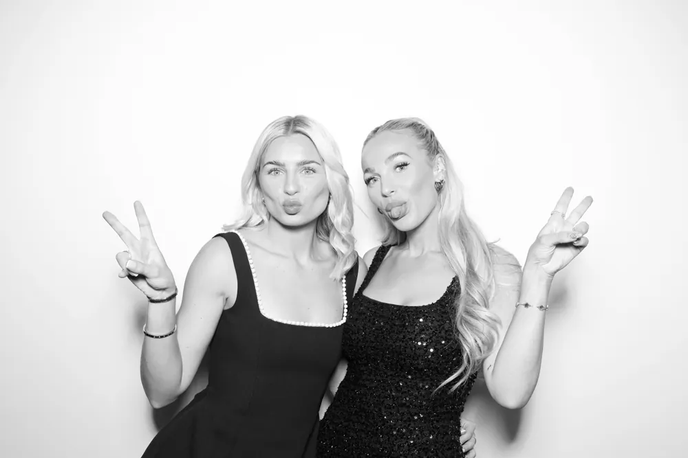 Two guests posing in a black-and-white Glam Booth photograph