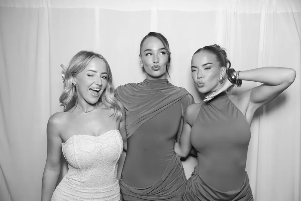 Three guests photographed against soft white drapes