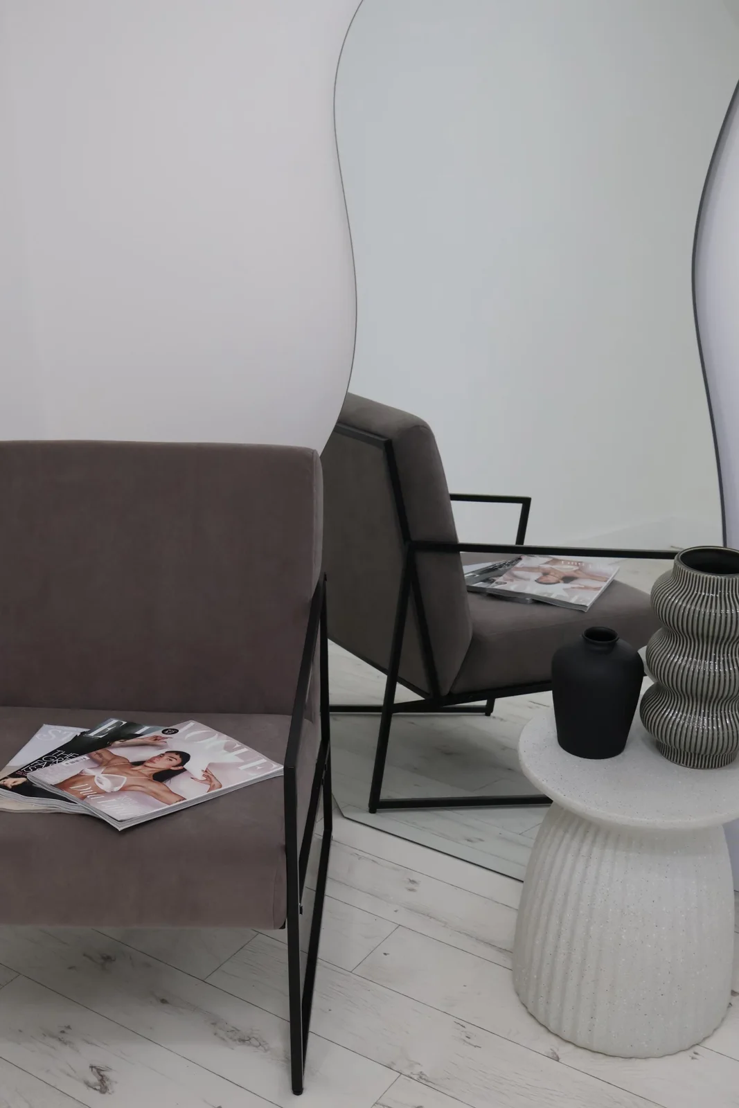 Grey armchair beside a sculptural mirror at Selfie Studios